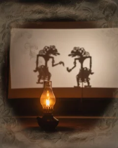 Filosofi Wayang Lampu blencong menerangi kelir wayang; bayang-bayang tokoh menari lembut sebagai metafora perang batin